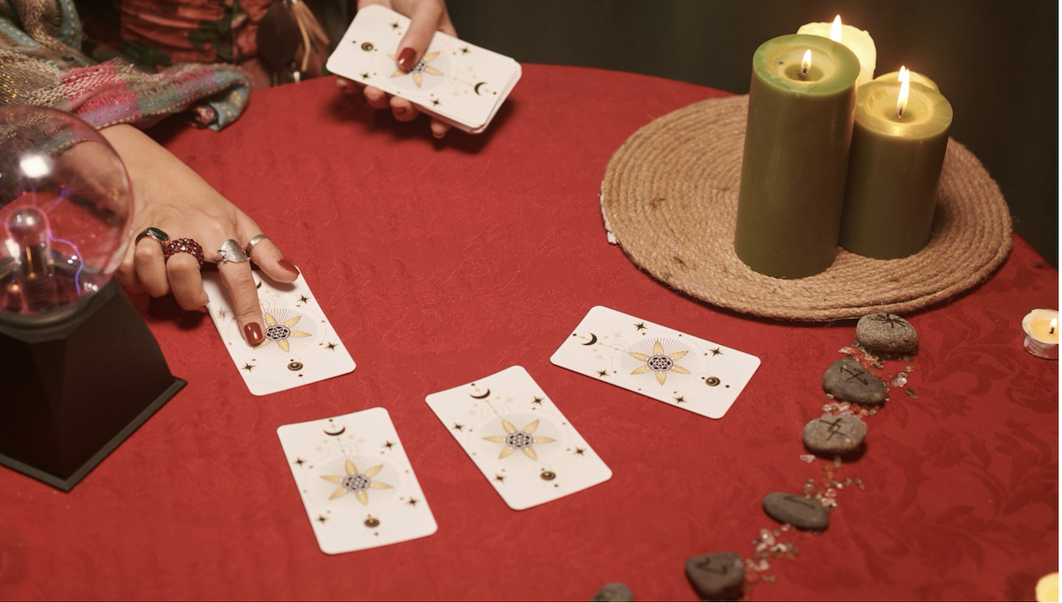 Tavolo rosso con carte, candele e mani durante una lettura