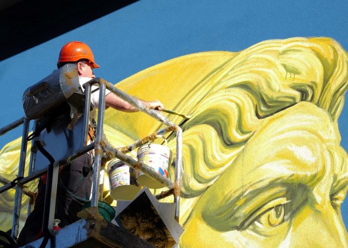 L'artista Ozmo all'opera sul murale di Giano Bifronte alla scuola "Pezzoli"