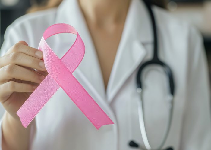 Doctor is holding a pink ribbon, representing breast cancer awareness and support for patients - prevenzione tumore al seno