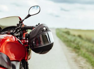 Black motorcycle helmet hanging on the handlebars of the motorcycle - stock - Moto