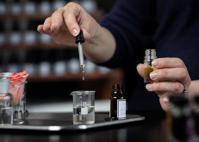 Perfumer making a perfume with tweezers Perfume bottles in the shelves in the blurry background