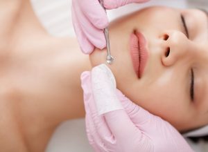 Young woman gets facial cleansing in a cosmetologist's office Skin cleaning at beauty salon Beautician squeezing pimples and blackheads from face - punti neri