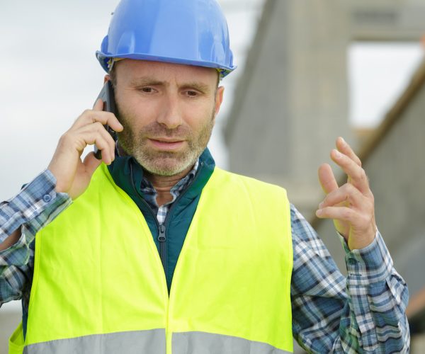 stressed workman gesturing during telephone conversation