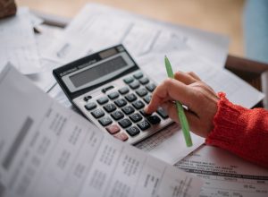 The hands of an elderly woman with a calculator and a lot of utility bills Pensioner and payment of utilities for heating - stock - Pensioni