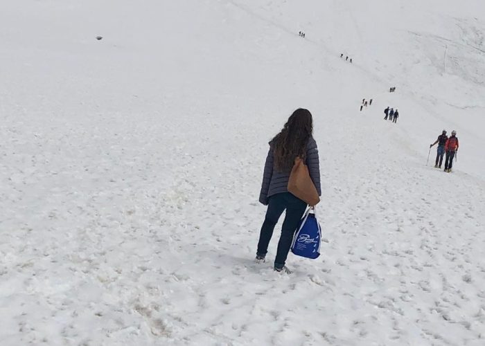 La donna in attesa sul ghiacciaio in jeans e scarpe da ginnastica.