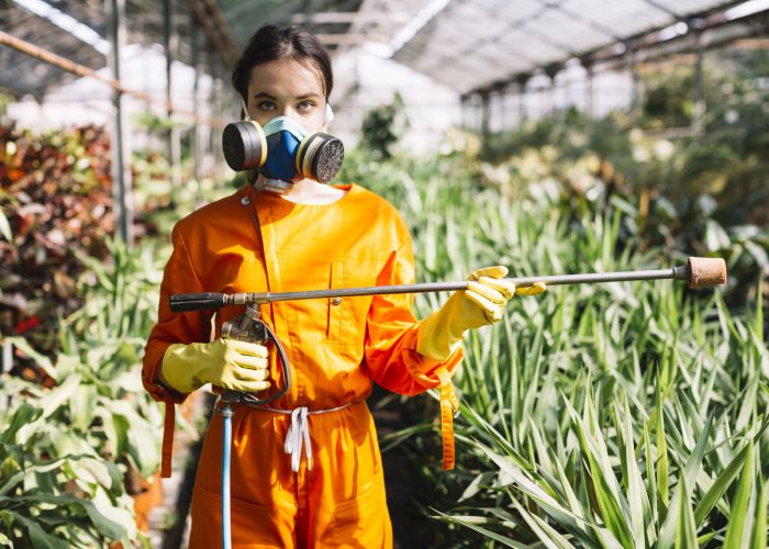 ritratto di un giardiniere femminile che tiene spruzzatore in serra